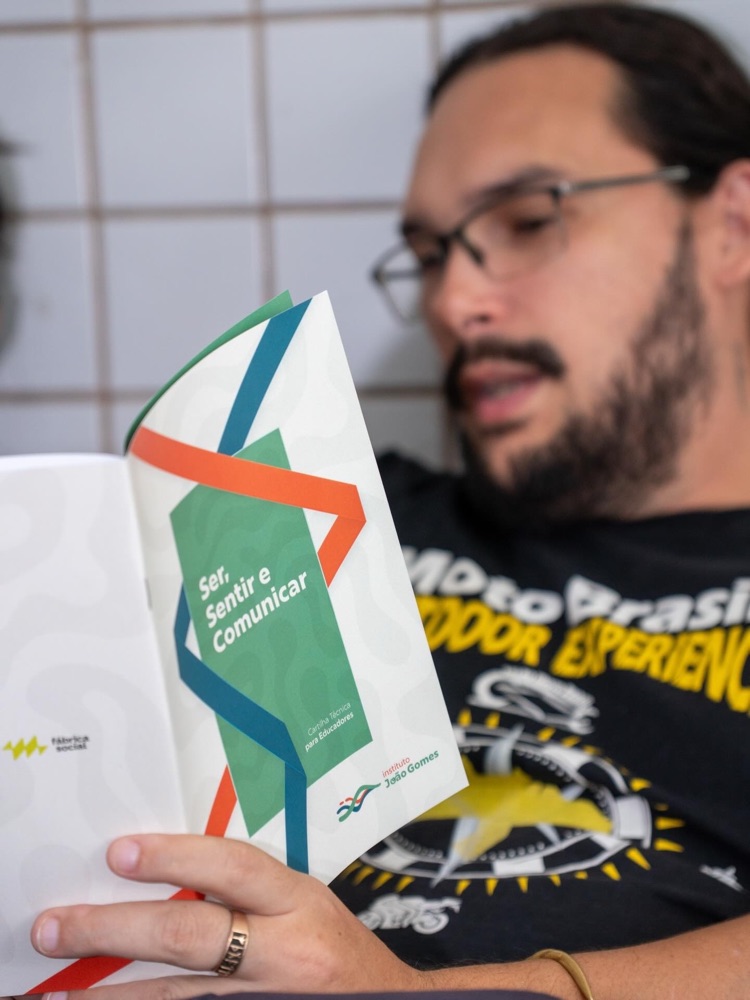 Educador segurando a cartilha impressa